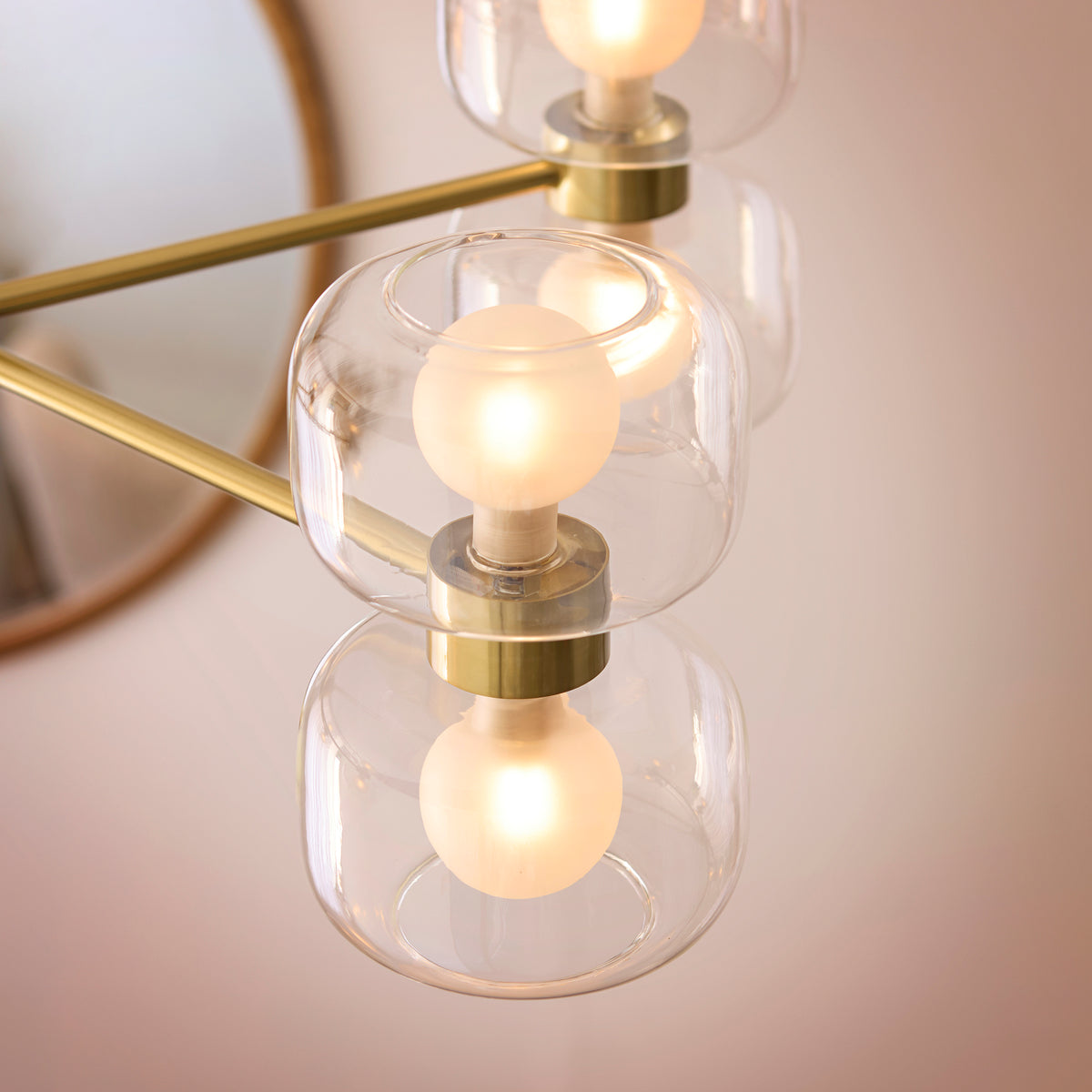 Close-up of stacked clear glass shades and lit frosted globes on the Rossano brass chandelier
