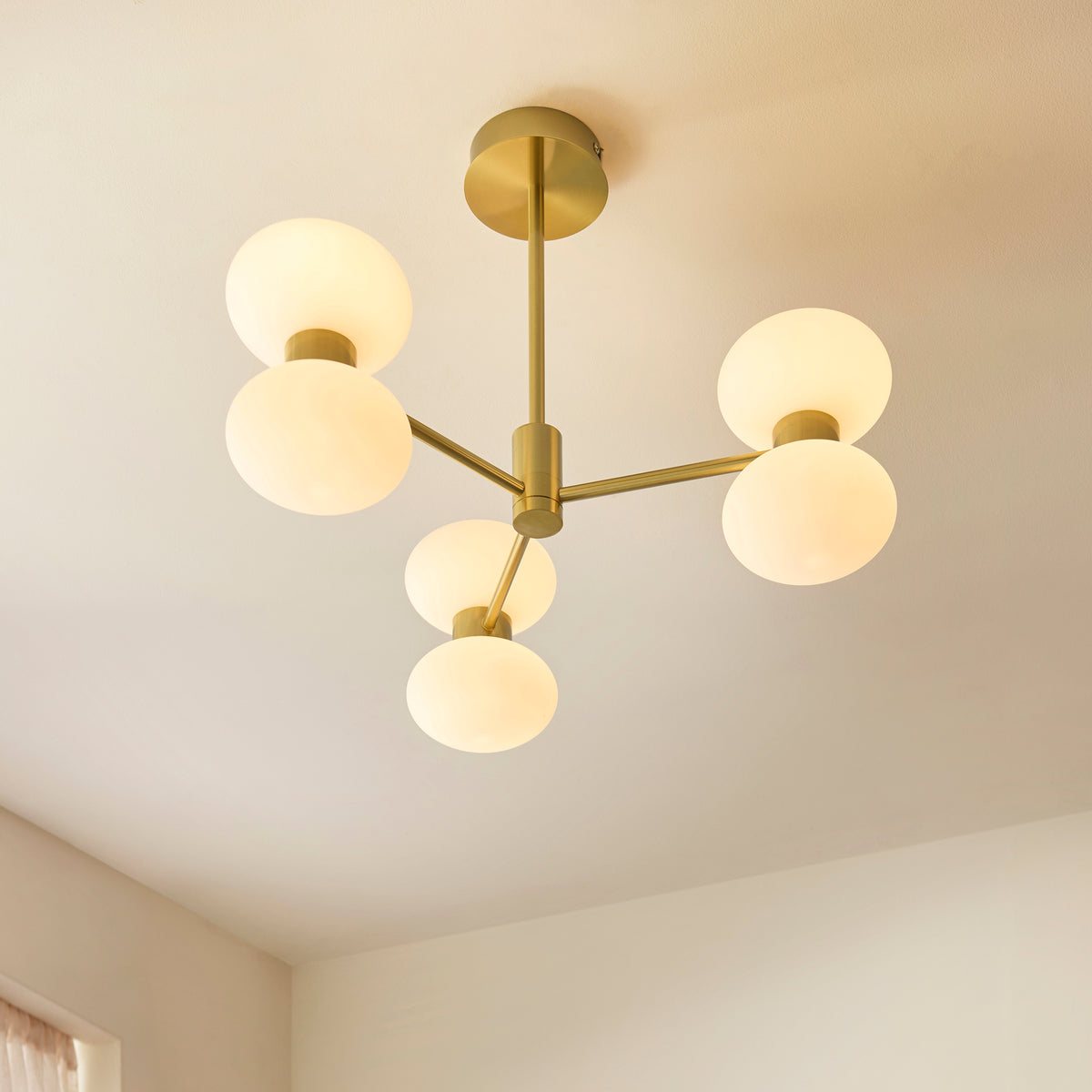 Close-up of the brass hub and arms holding opal glass shades on the Rossano ceiling light