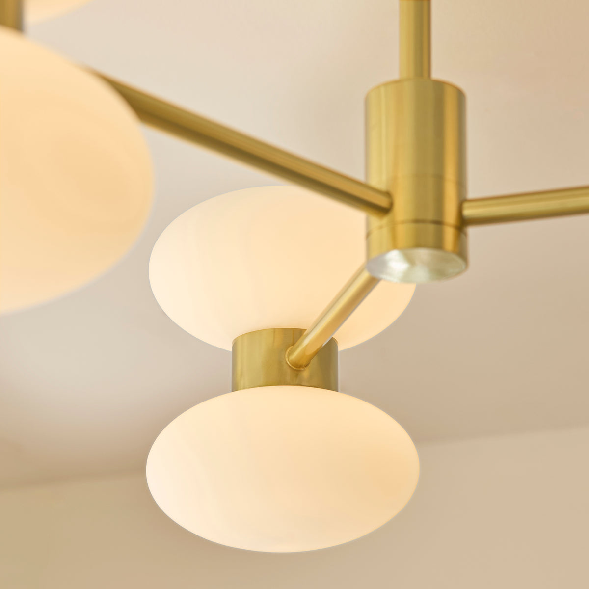 Detail of two opal glass oval shades and brushed brass collar on the Rossano ceiling light