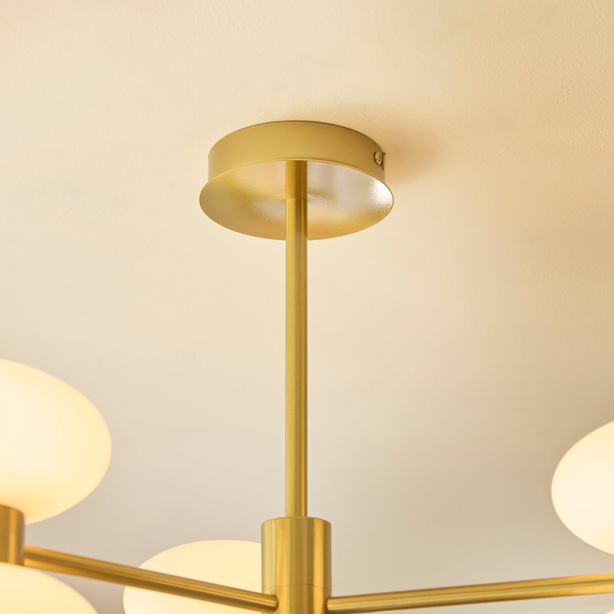 Rossano brass semi flush ceiling light viewed from the side with five opal glass shades