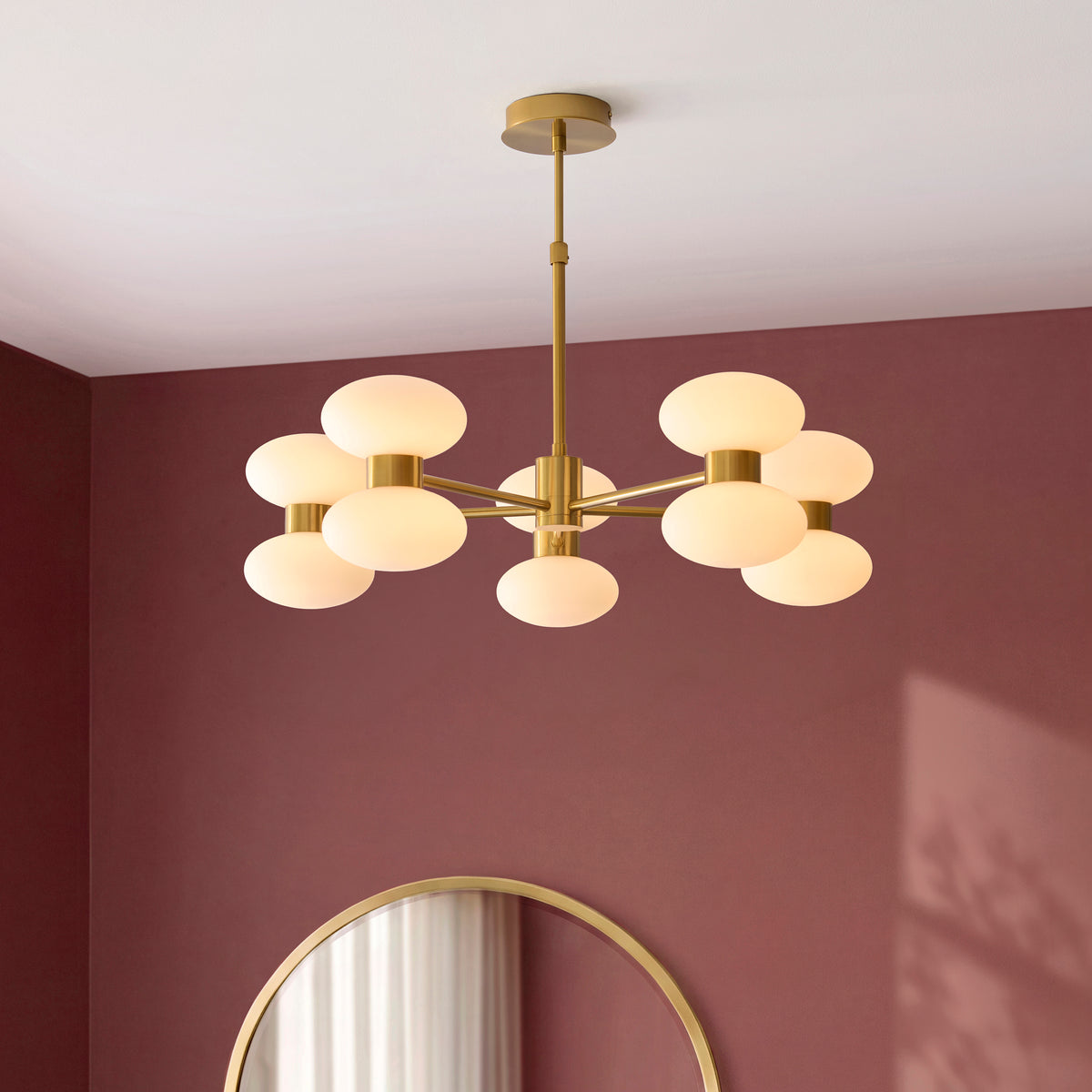 Rossano brass pendant with opal glass shades hanging in a burgundy-walled room