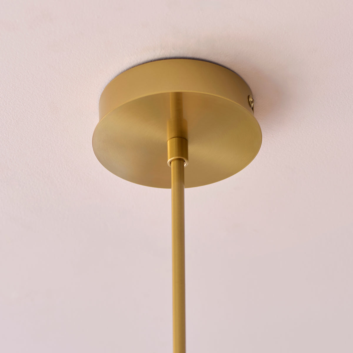 Close-up of the Rossano pendant's brass ceiling rose and adjustable stem