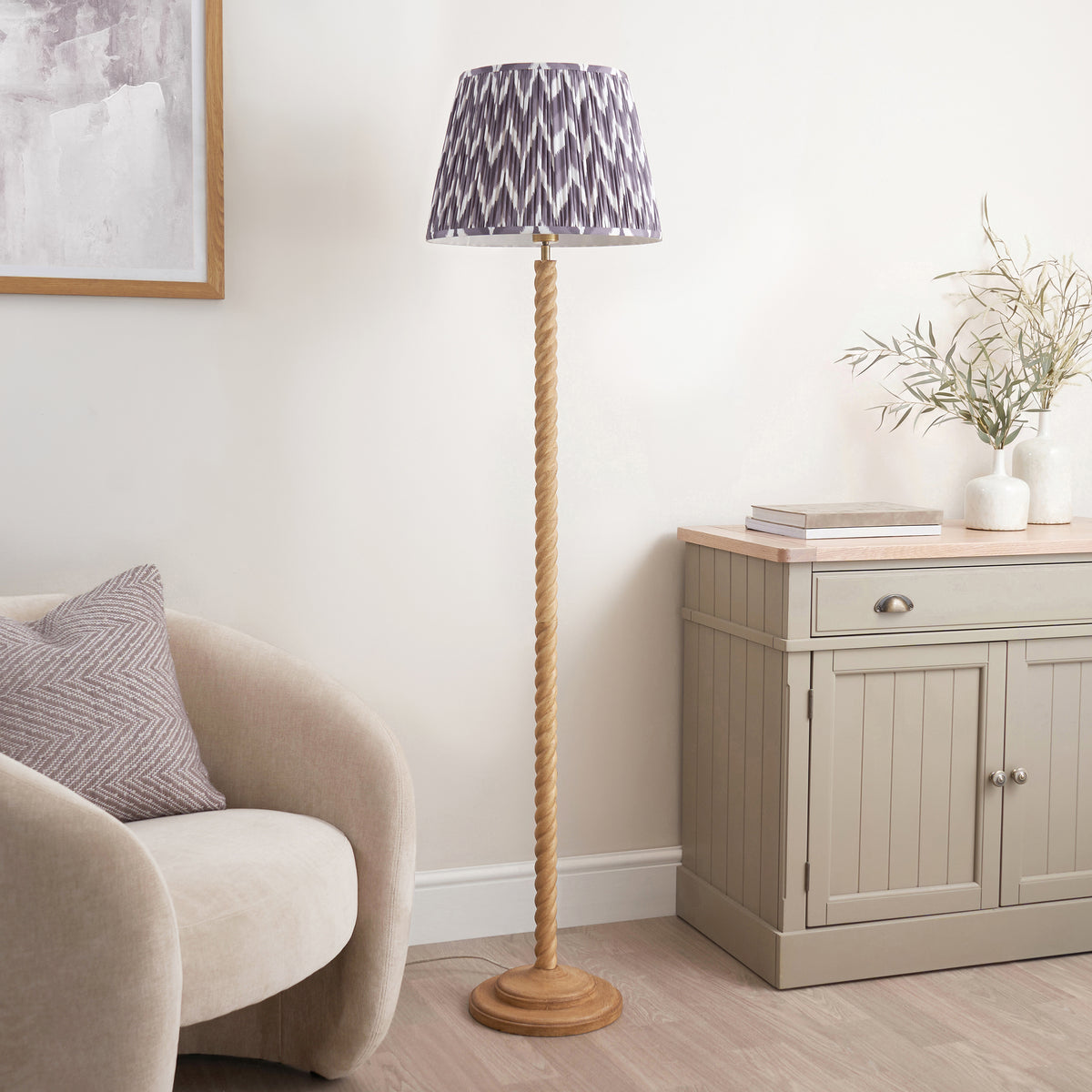 Oak effect twisted floor lamp with grey zigzag pleated shade in a neutral living room corner