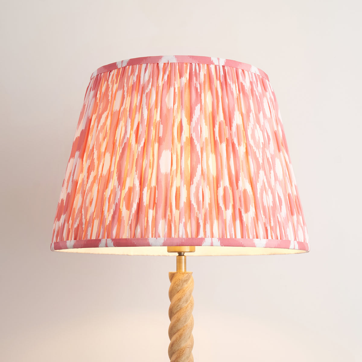 Close-up of the pleated coral pink and white ikat fabric shade on the Twist floor lamp