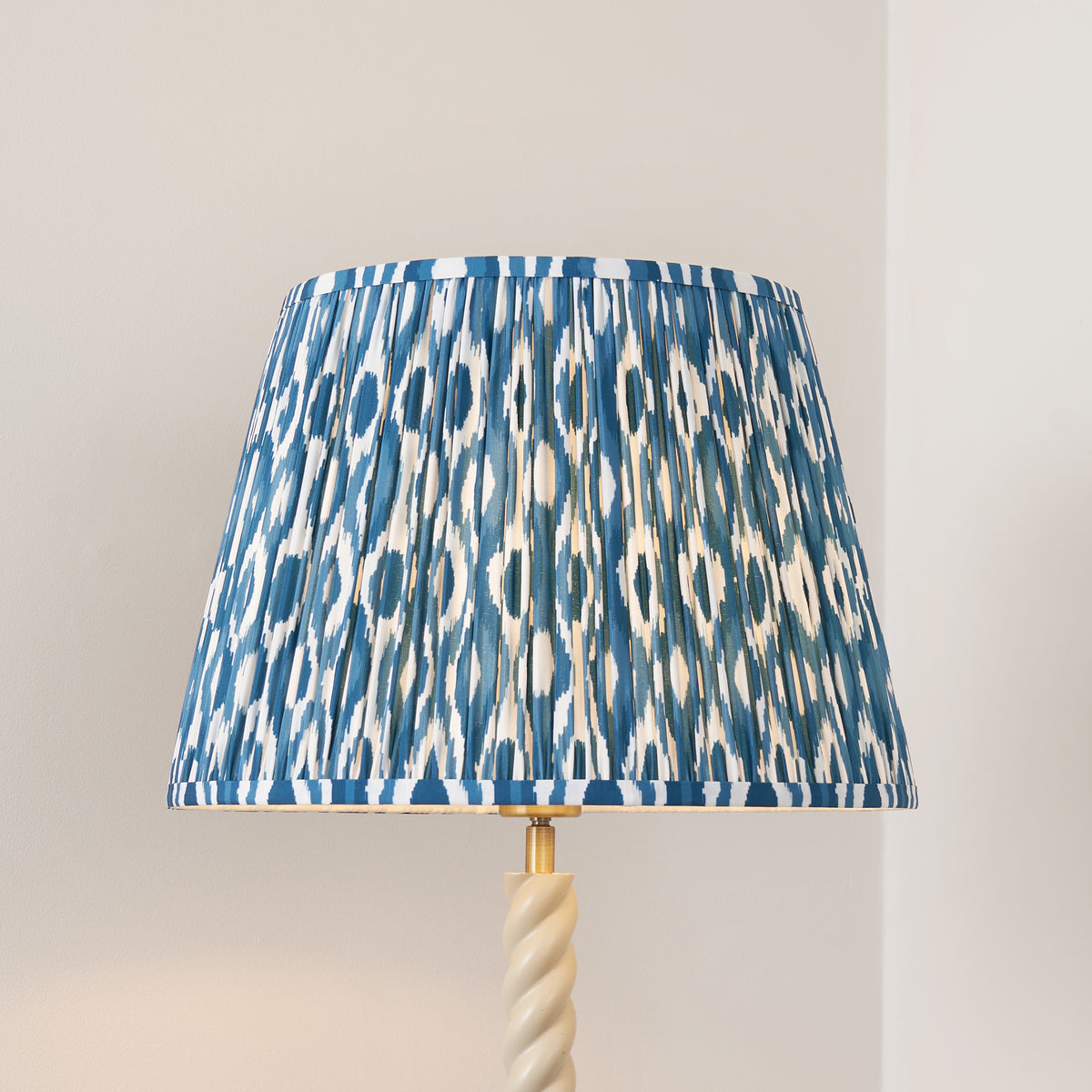 Close-up of the pleated blue and white ikat tapered shade above the twisted almond white stem