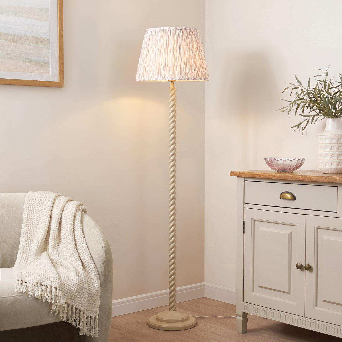 Twist Satin almond white floor lamp with neutral ikat shade lit beside a cream sideboard and armchair