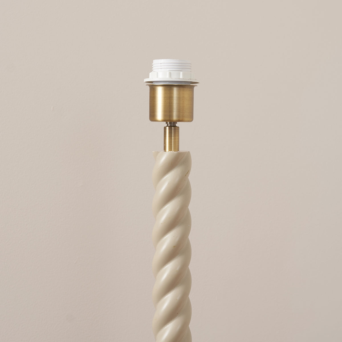 Antique brass lampholder above the twisted almond white floor lamp stem
