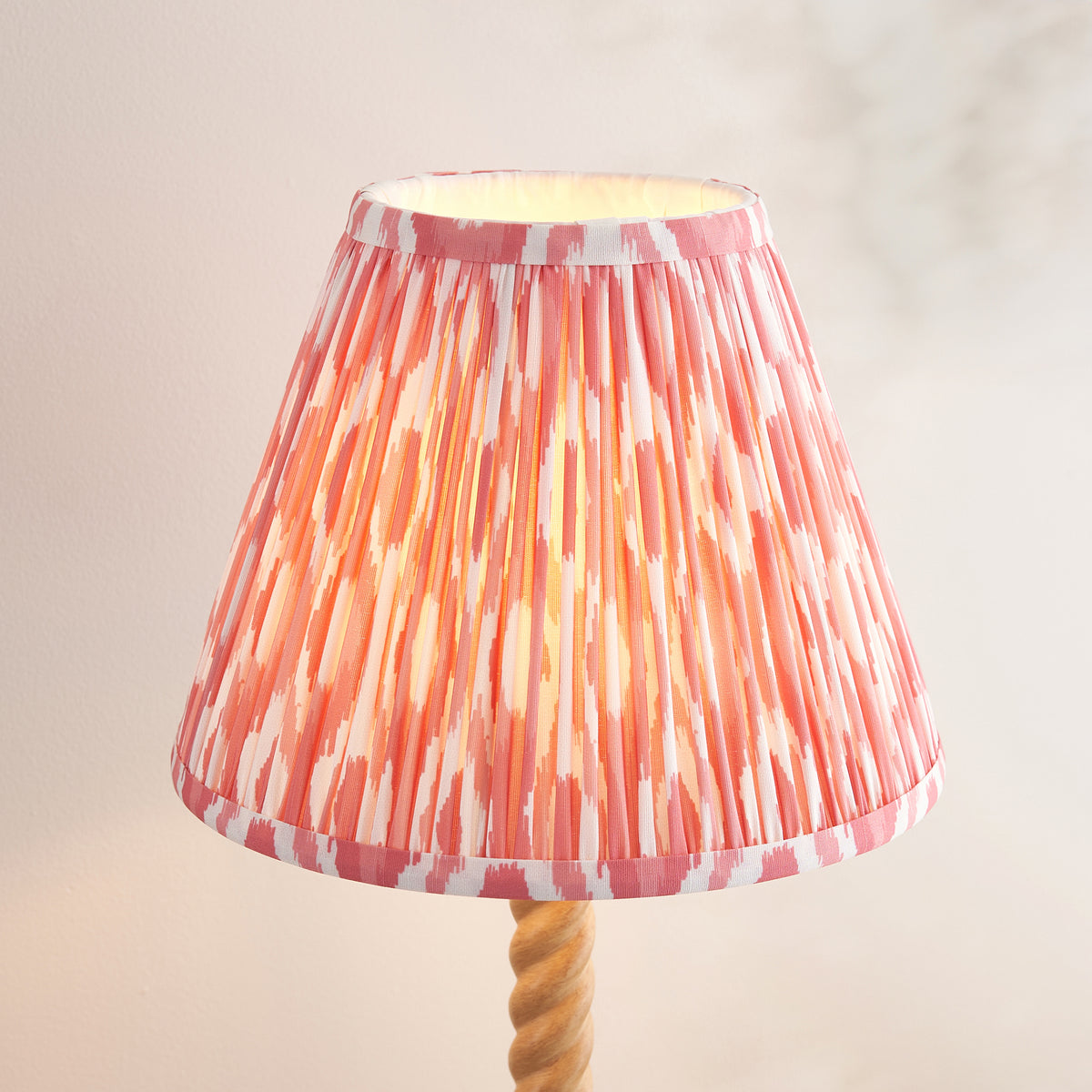 Close-up of the pleated coral pink and white ikat shade glowing above the twisted stem