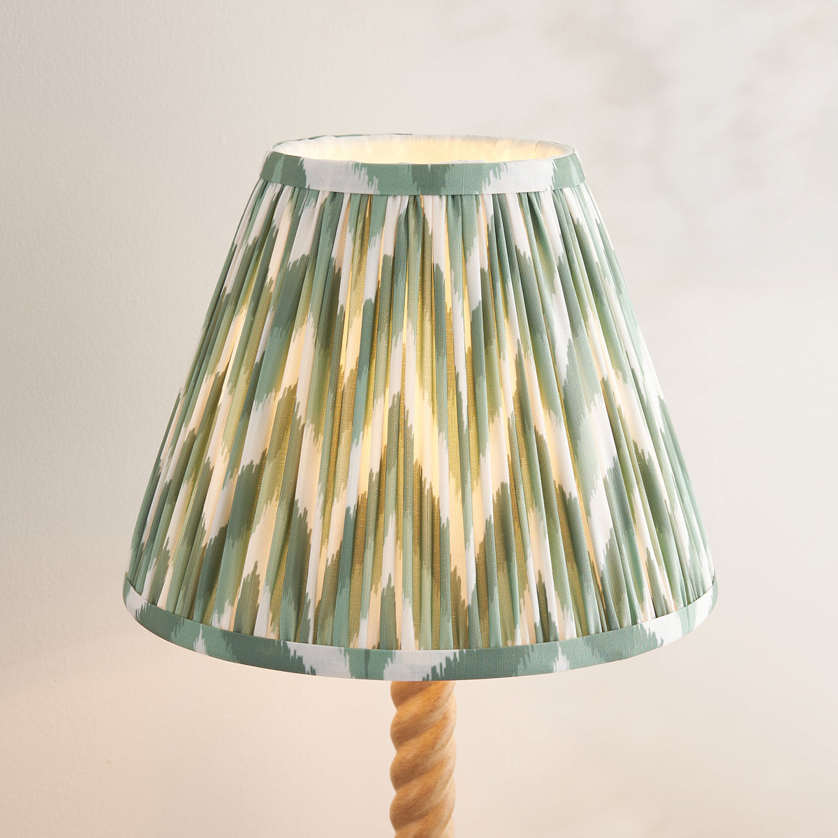 Close-up of the pleated green, gold and cream zigzag ikat shade above the twisted stem