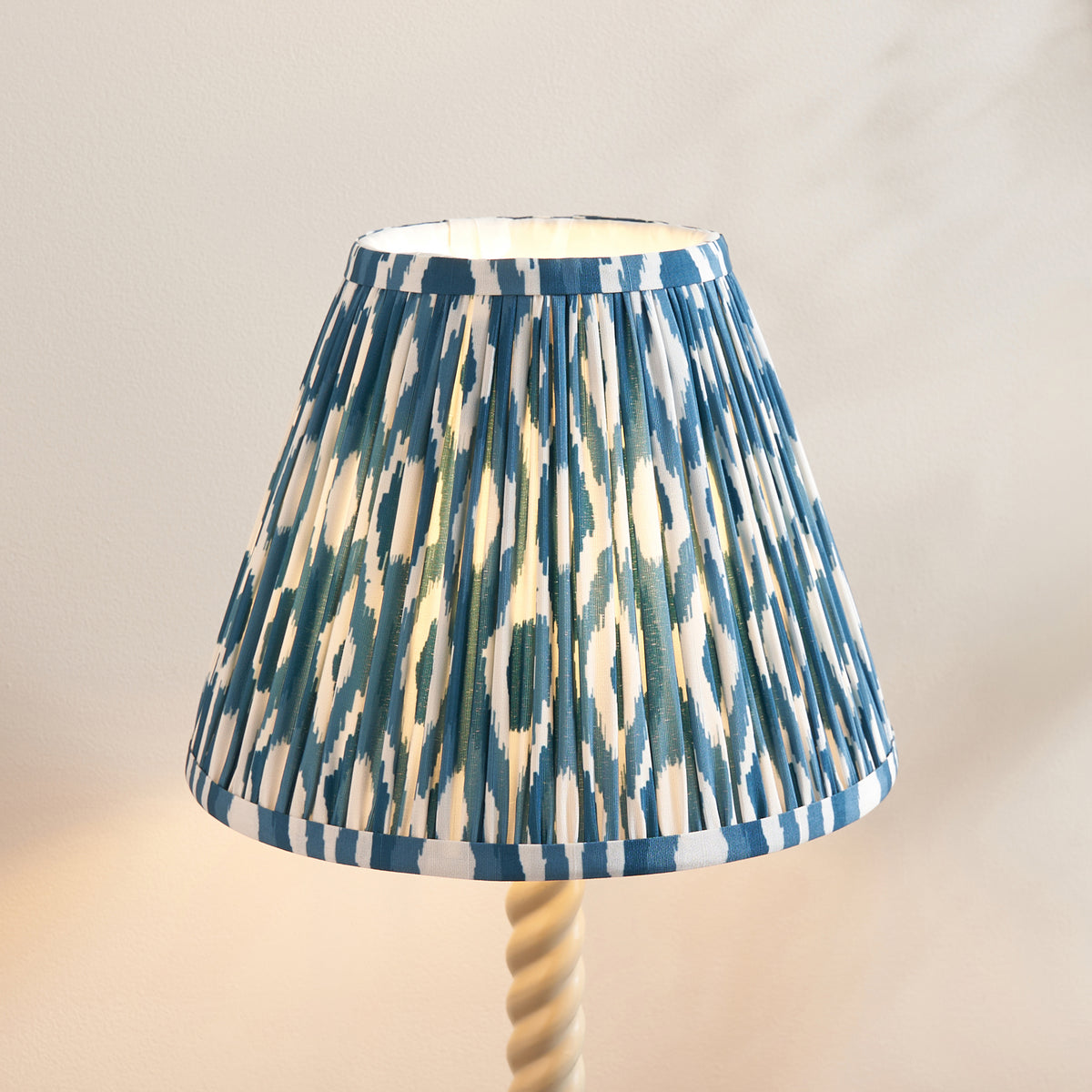 Close-up of the pleated blue and cream ikat shade above the almond white twisted stem