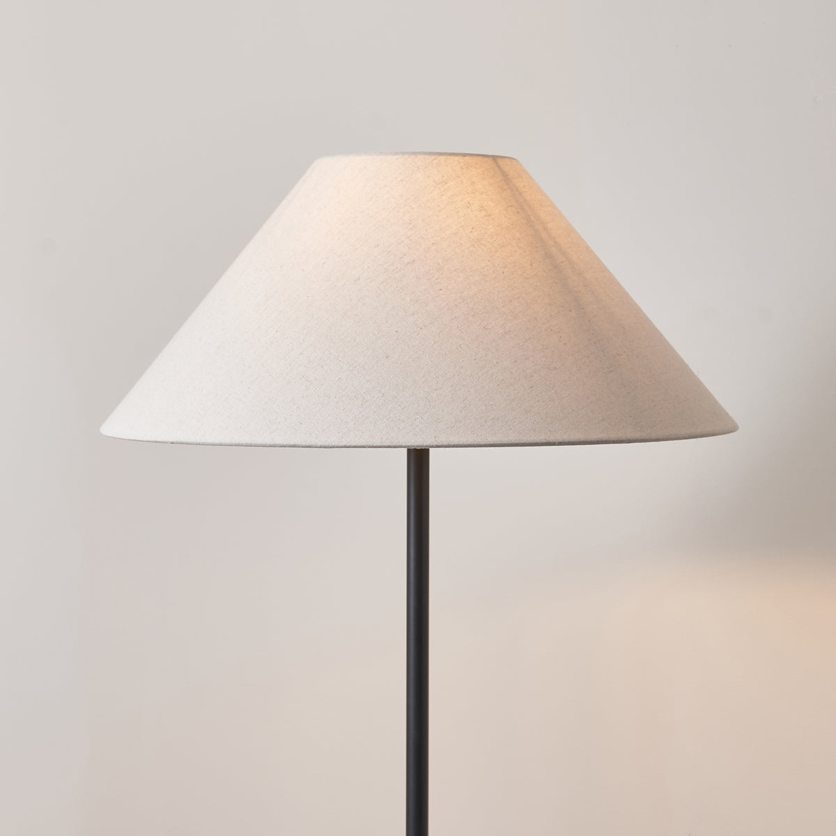 Close-up of the wide natural linen coolie shade on the Arlo matt black floor lamp