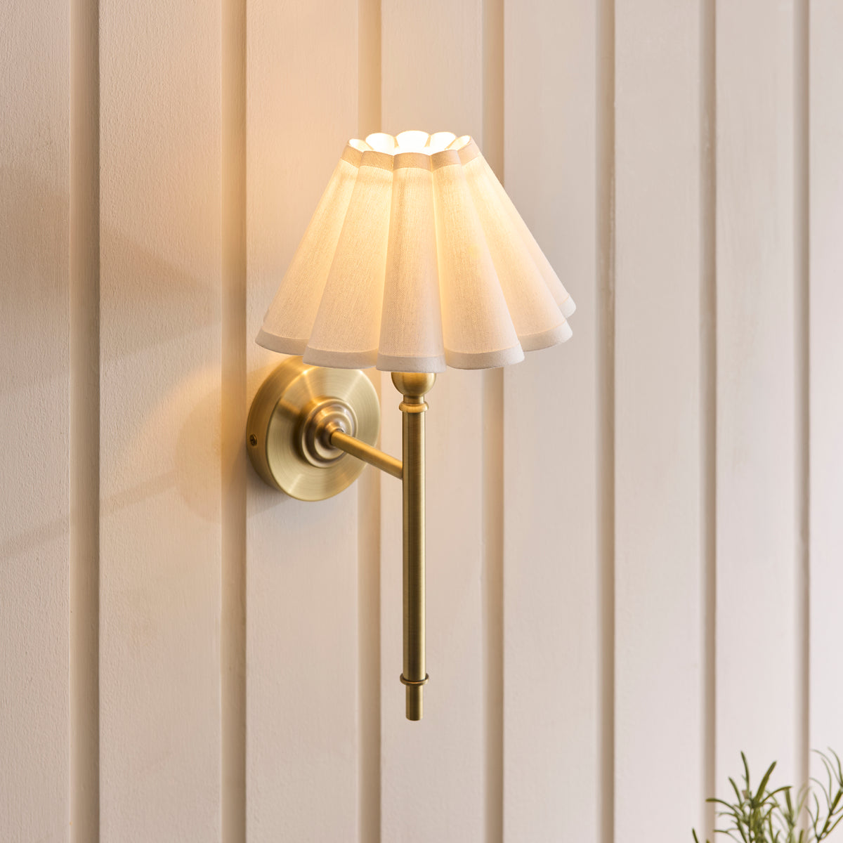 Angled view of the antique brass Sylvie wall light with its pleated white shade