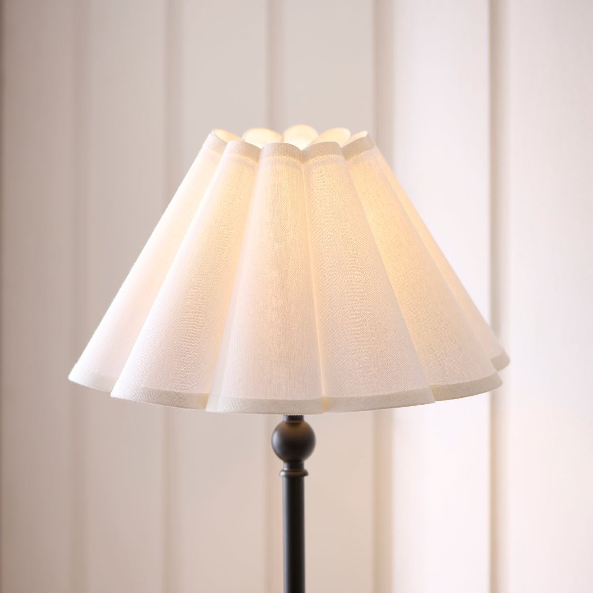 Close-up of the Sylvie table lamp's scalloped white shade above its black stem