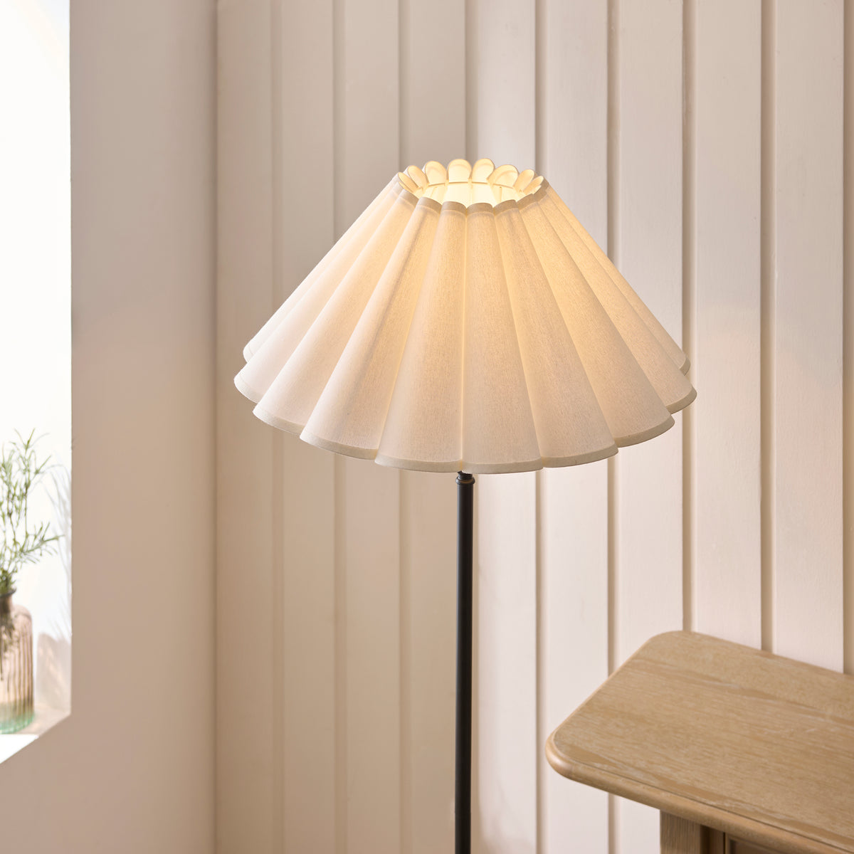 Close-up of the Sylvie floor lamp's pleated white shade seen from above beside a wooden table
