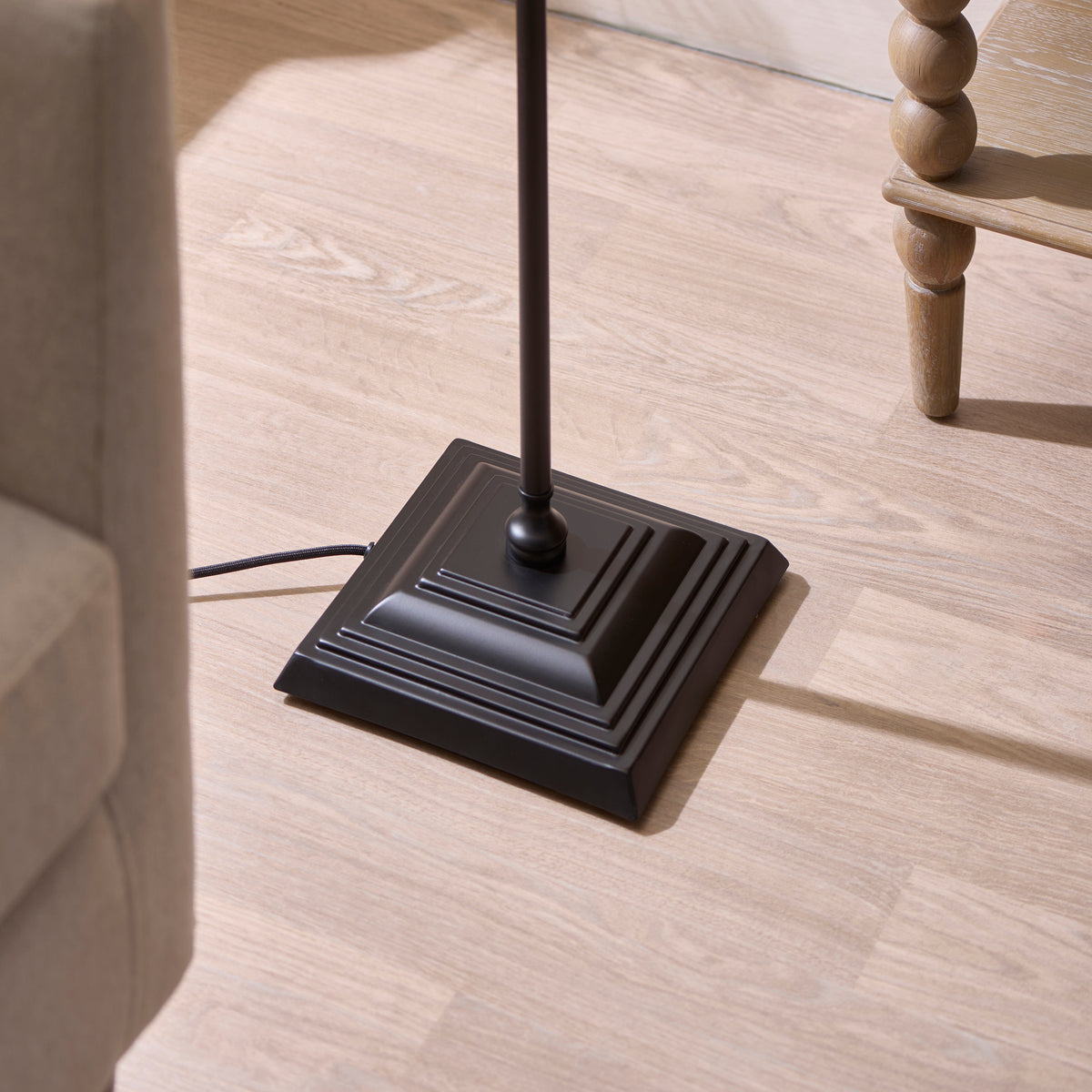 Stepped square black base of the Sylvie floor lamp on pale wood flooring