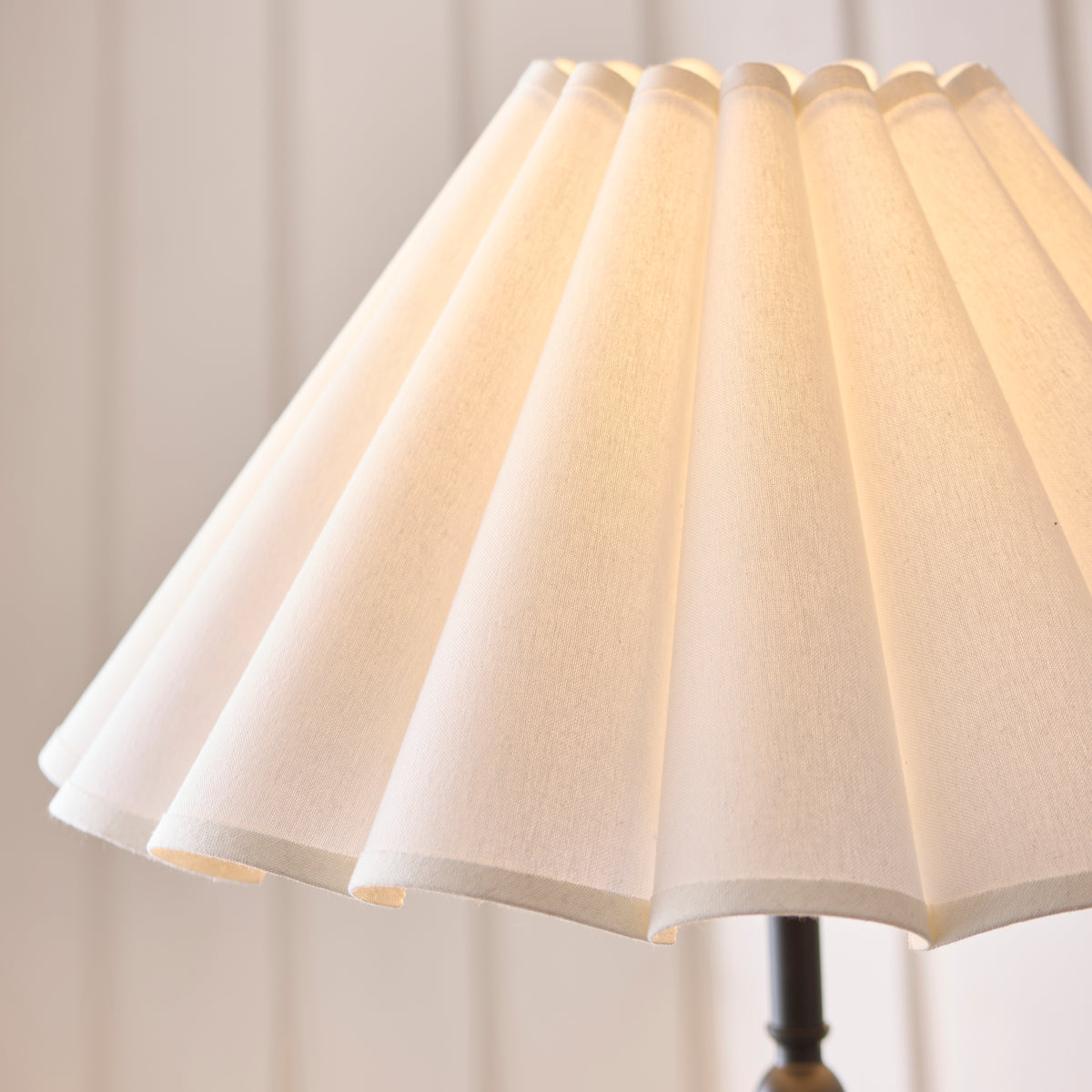 Close-up of the warmly lit scalloped white linen shade on the Sylvie floor lamp