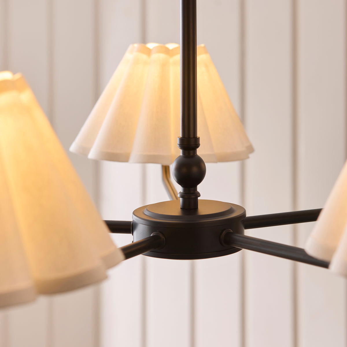 Close-up of the matt black centre hub, arms and pleated shades of the Sylvie pendant