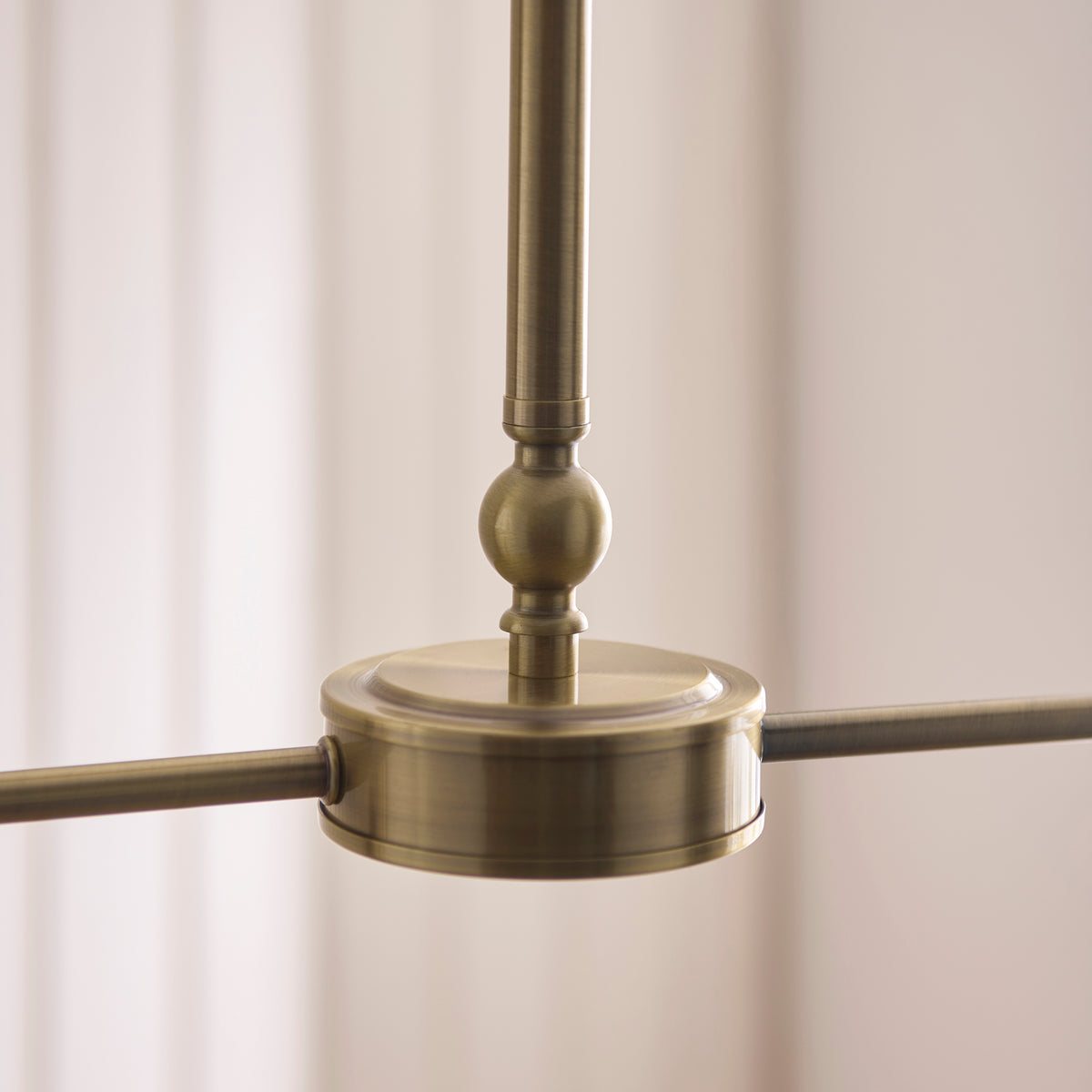Detail of the Sylvie linear pendant's antique brass hub, ball detail and slim stem