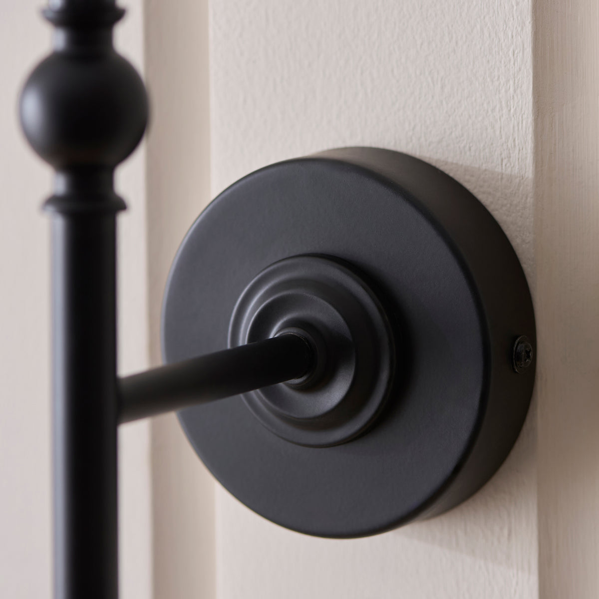 Detail of the Jericho wall light's stepped matt black round backplate and arm