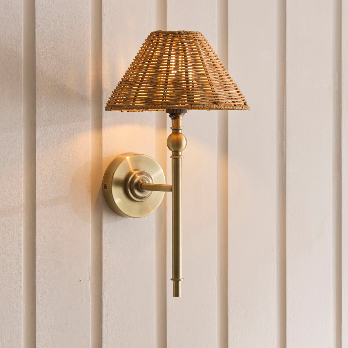 Jericho antique brass wall light glowing warmly against a panelled wall
