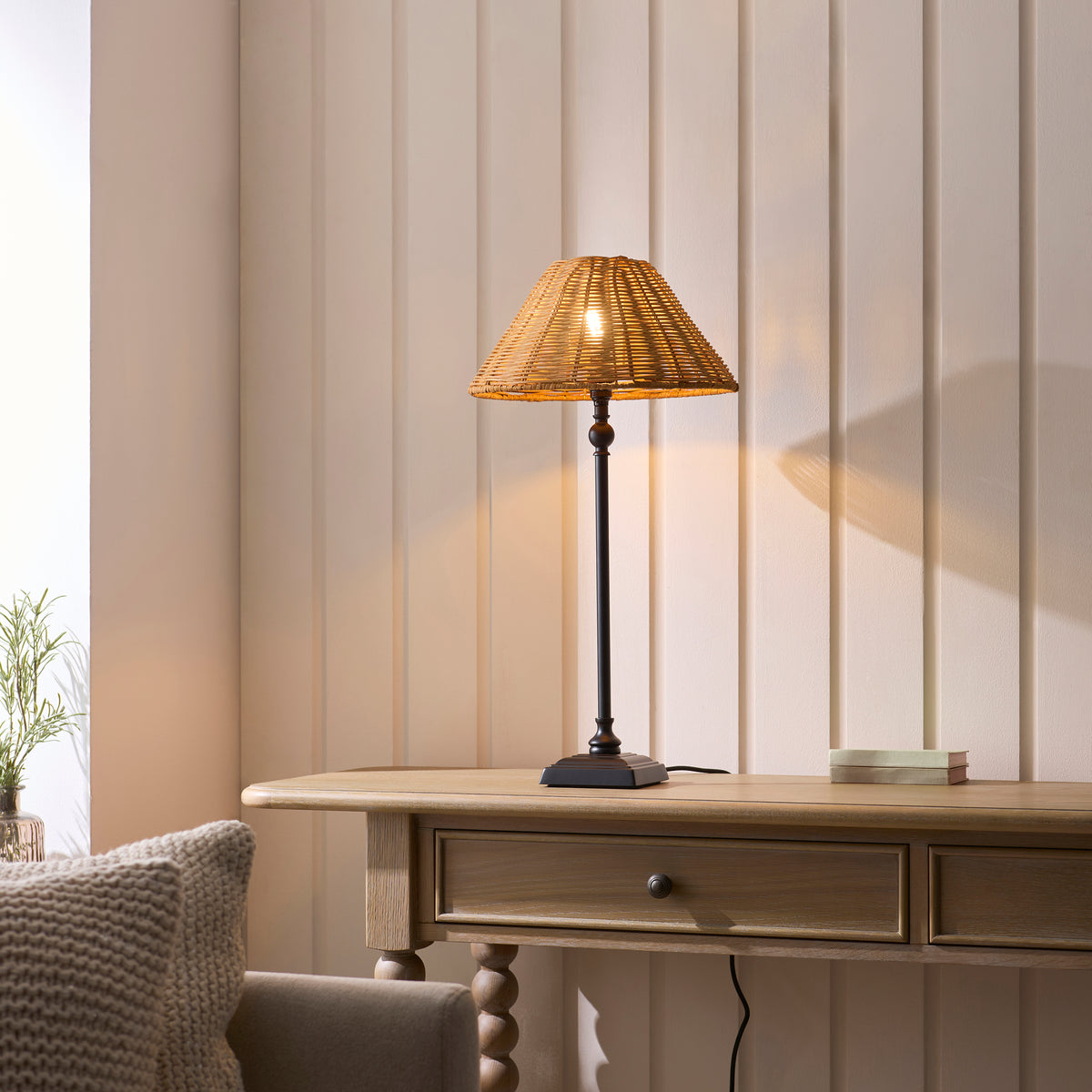 Jericho black table lamp glowing on a console table beside a knitted cushion and sofa