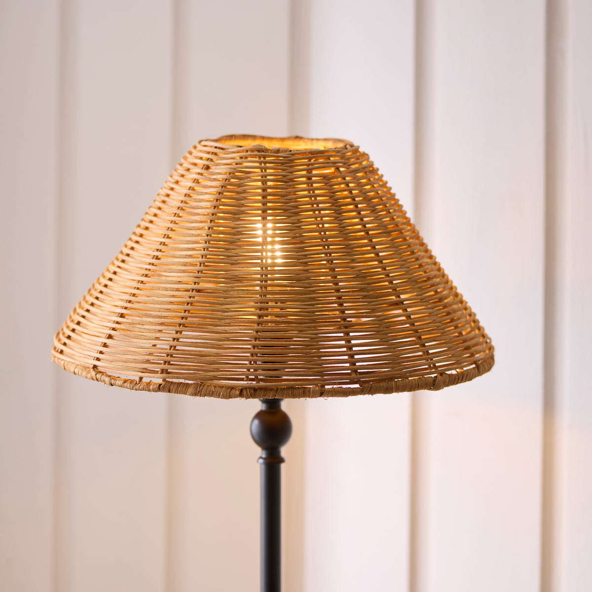 Close-up of the Jericho table lamp's natural rattan coolie shade glowing above its black stem