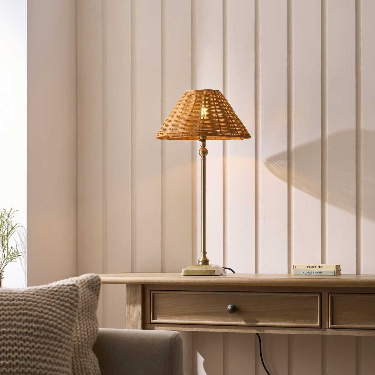 Jericho brass table lamp lit on a wooden console table beside a cushioned sofa
