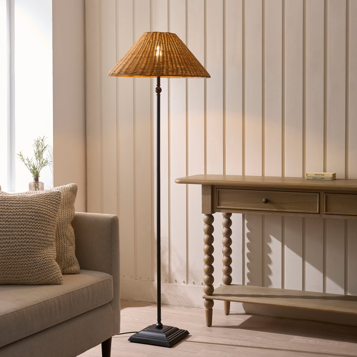Jericho black floor lamp lit beside a sofa and wooden console table in a panelled room
