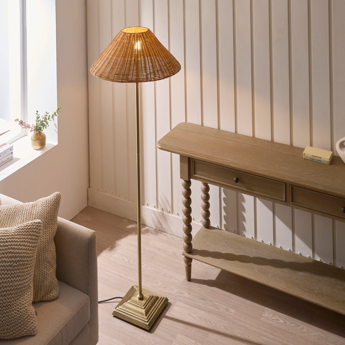 Lit Jericho rattan floor lamp in a panelled living room next to a bobbin-leg wooden console table