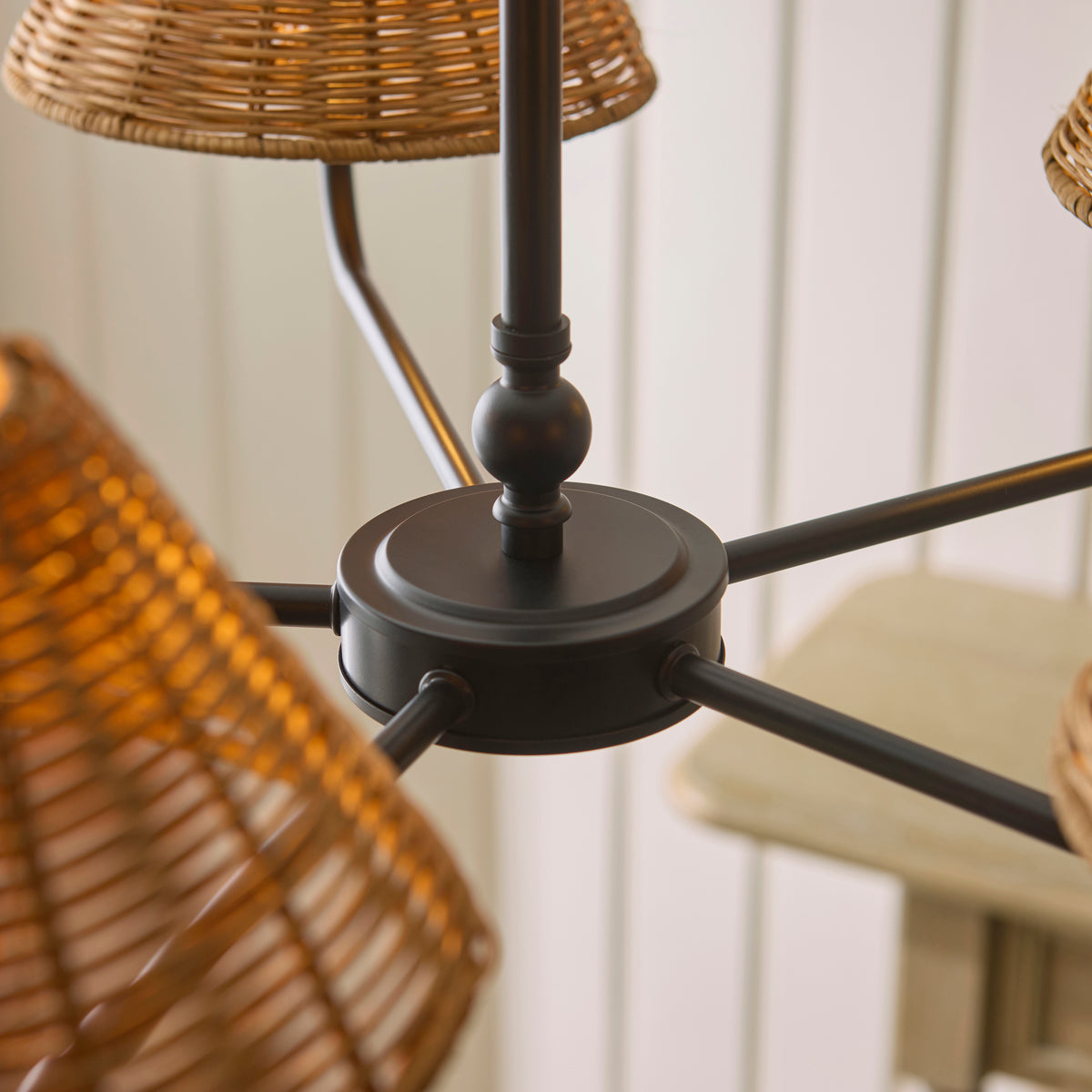 Matt black centre hub and arms of the Jericho pendant with rattan shades around it
