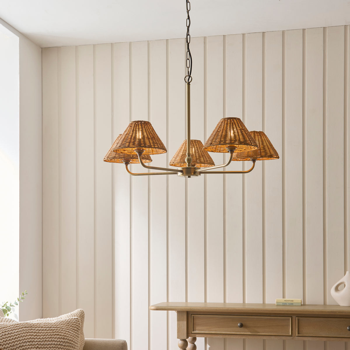 Jericho brass rattan chandelier lit above an oak console table in a panelled room