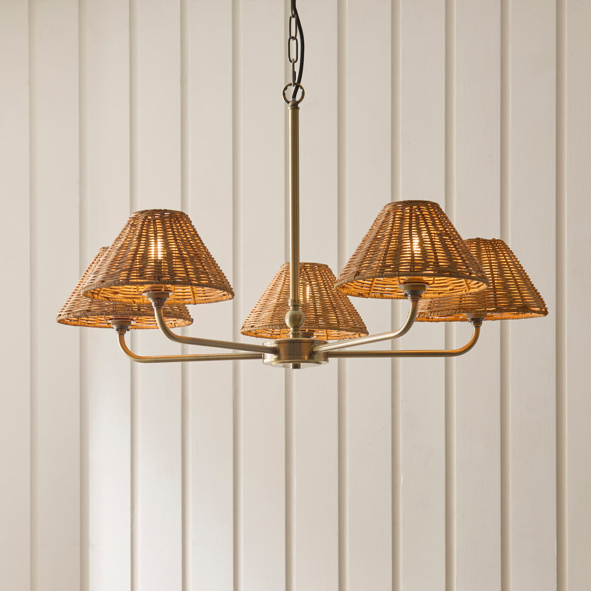 Five-light Jericho antique brass chandelier with rattan shades against cream panelling