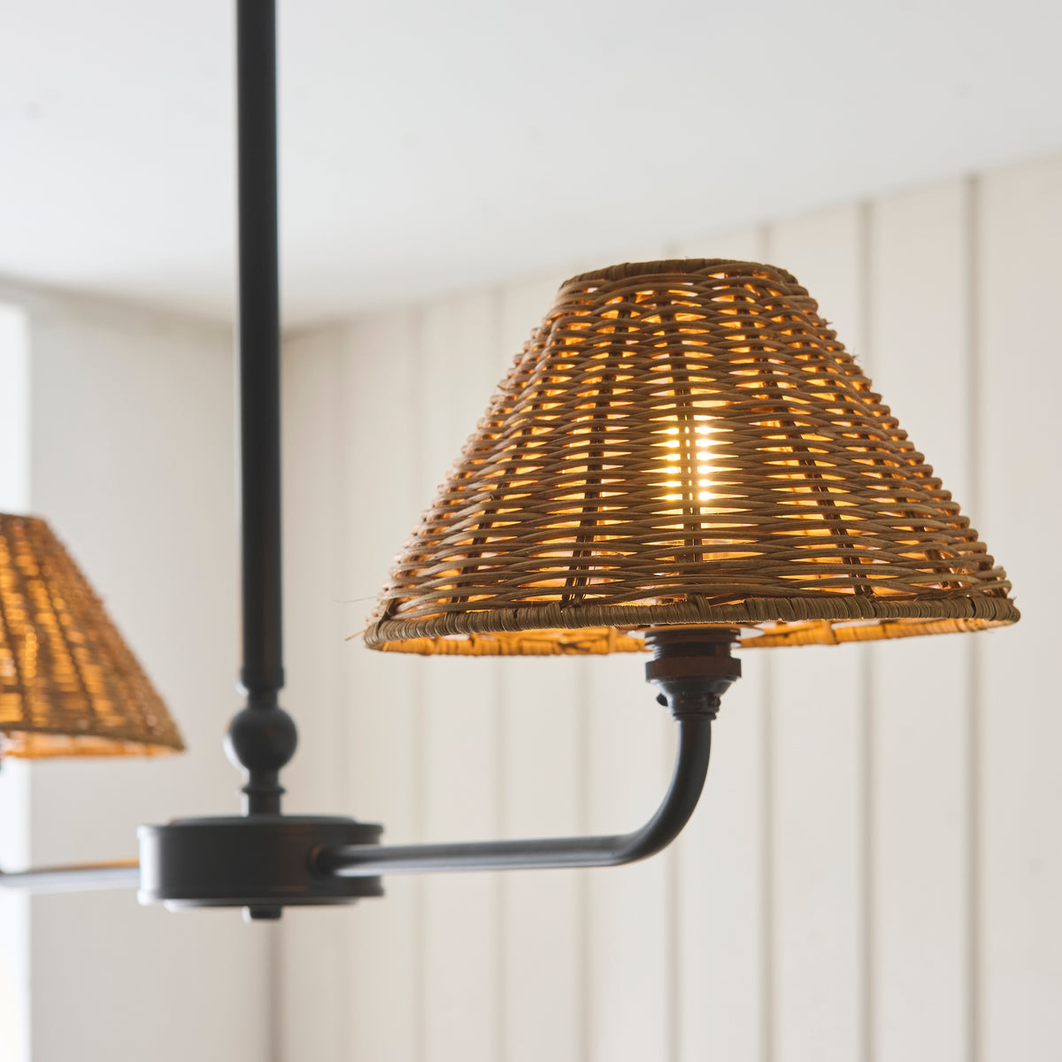 Close-up of a glowing brown rattan shade on the Jericho black linear pendant