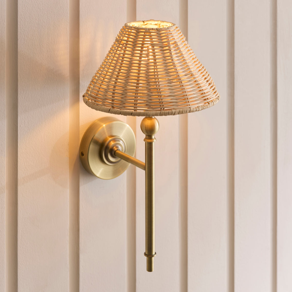 Angled view of the Jericho brass wall light with its natural rattan shade