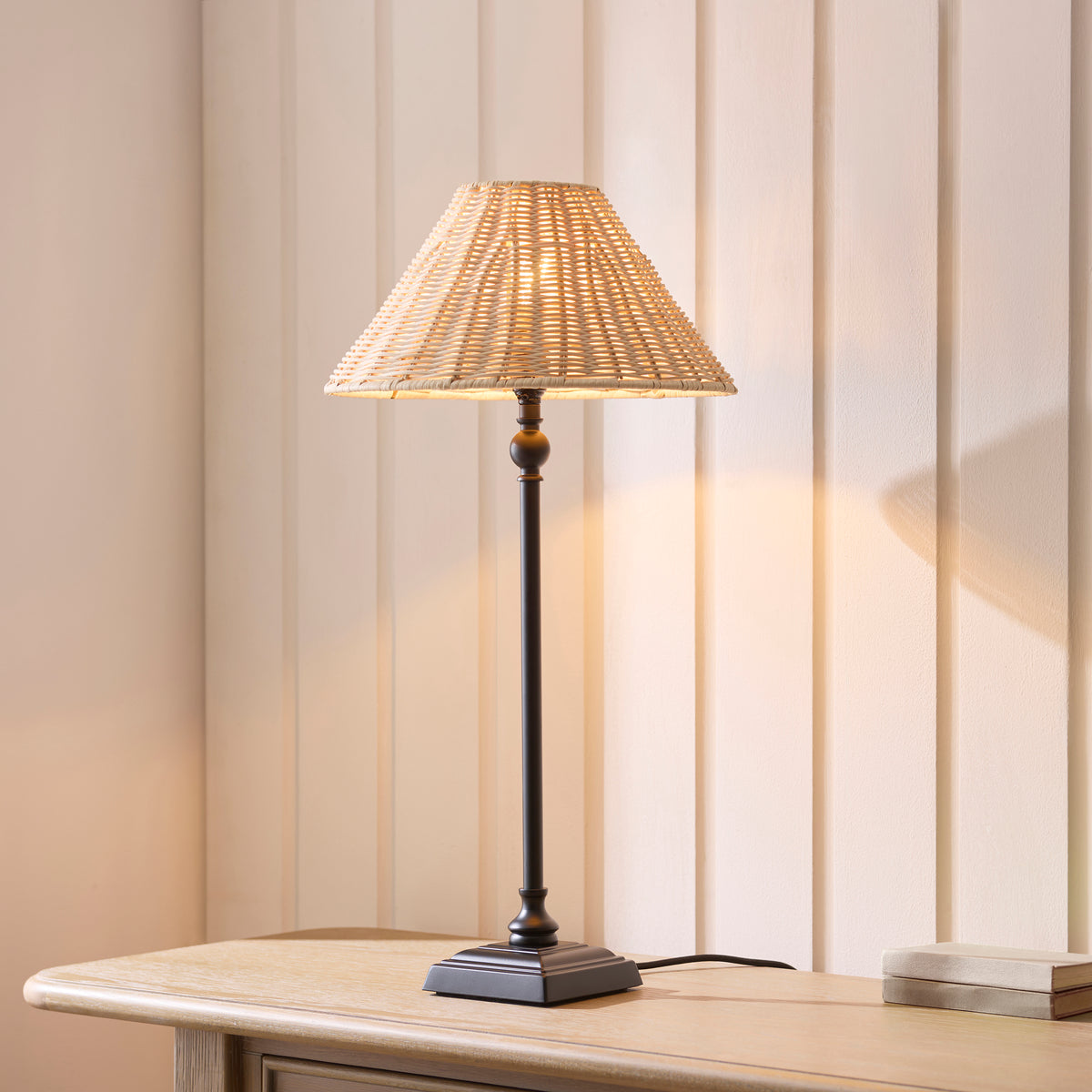 Jericho black table lamp glowing on a wooden sideboard against cream panelling