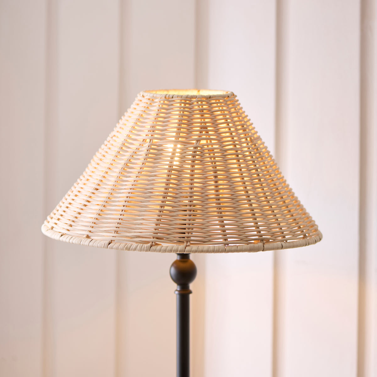 Close-up of the Jericho table lamp's glowing woven rattan shade and slim black stem