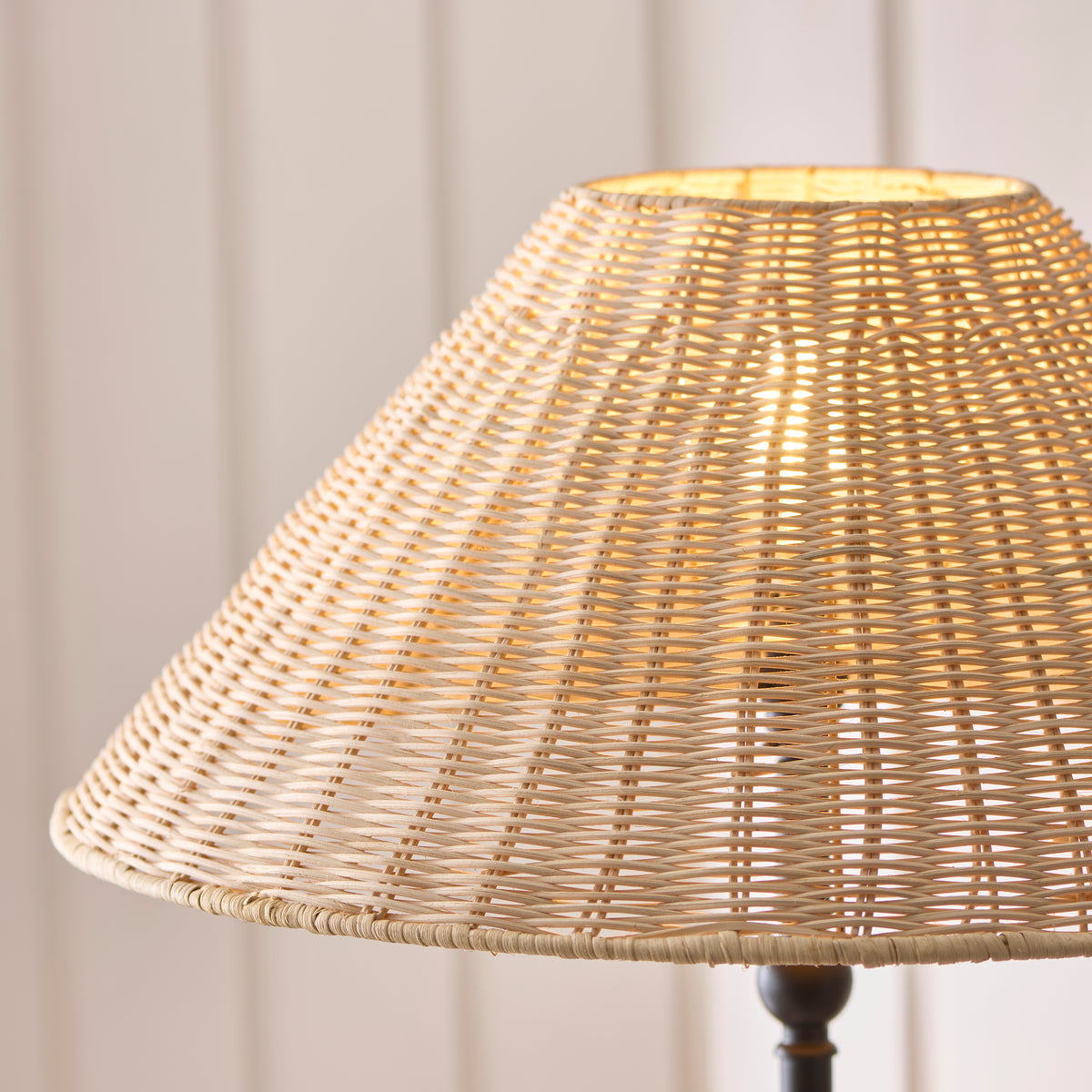 Close-up of the Jericho floor lamp's woven rattan shade glowing warmly