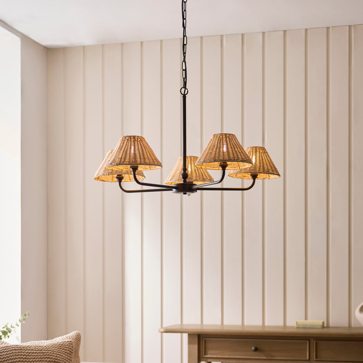 Jericho black five-arm pendant lit above a console table in a panelled room