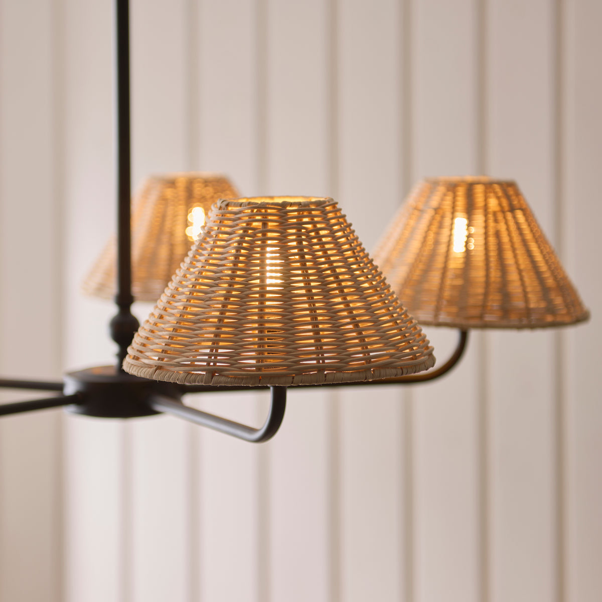 Close view of three glowing rattan shades on the Jericho black pendant