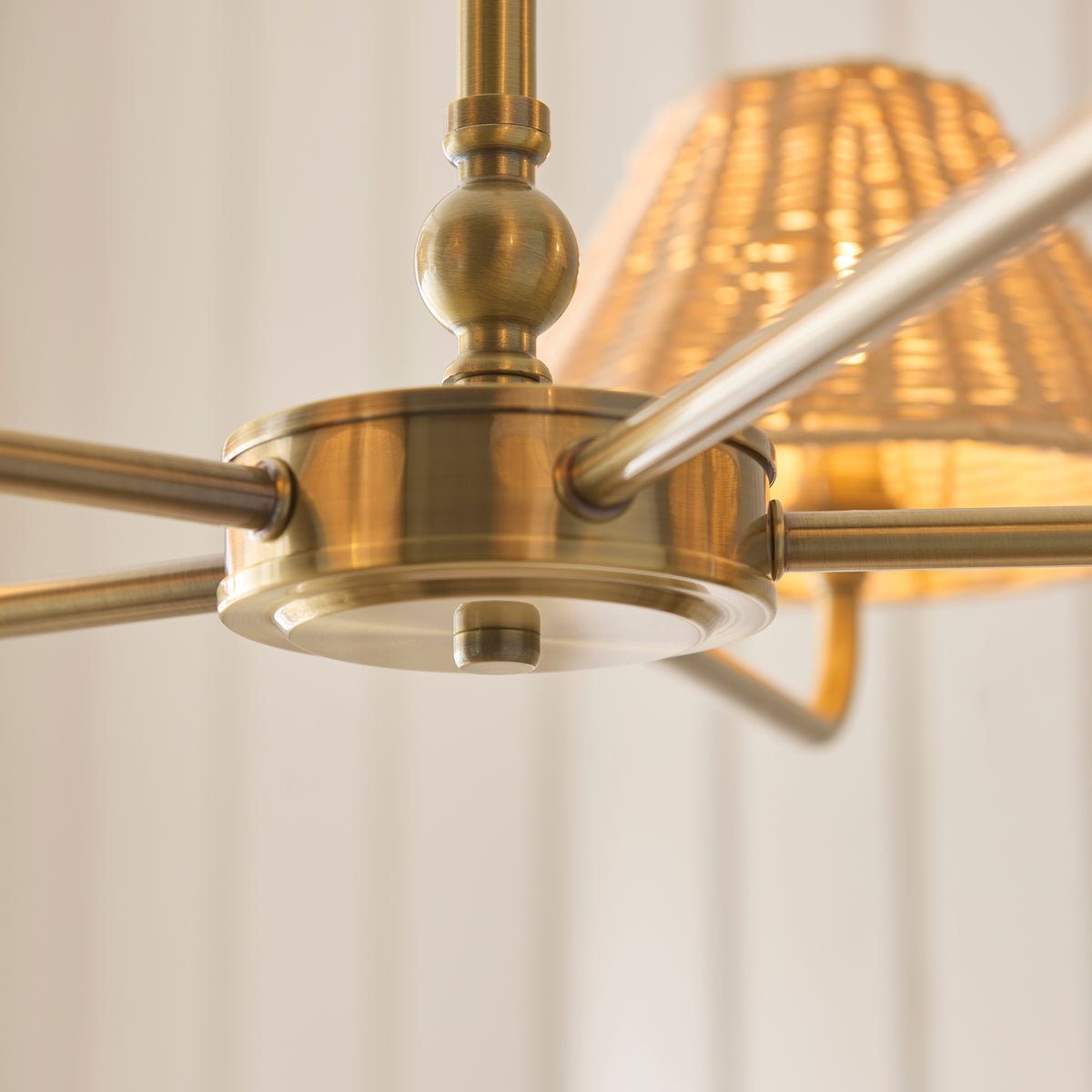 Antique brass hub and arms of the Jericho pendant from below with a lit rattan shade