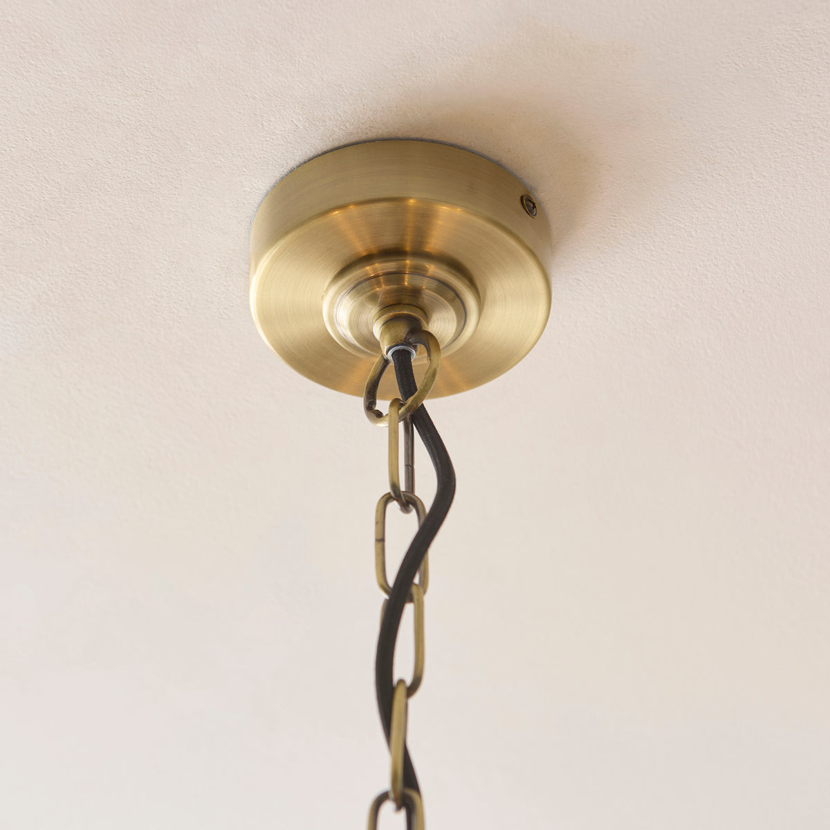 Antique brass ceiling rose and chain of the Jericho pendant on a white ceiling