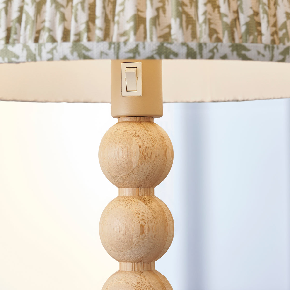 Close-up of the bamboo ball stem and rocker switch beneath the leaf-print pleated shade