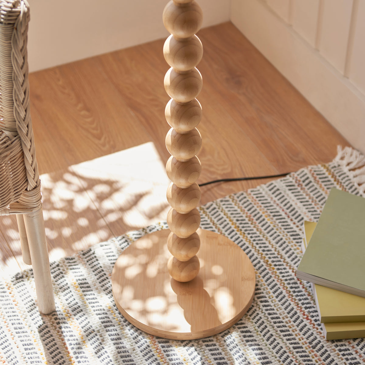 Stacked bamboo ball stem and round base of the Cane & Leaf floor lamp on a striped rug