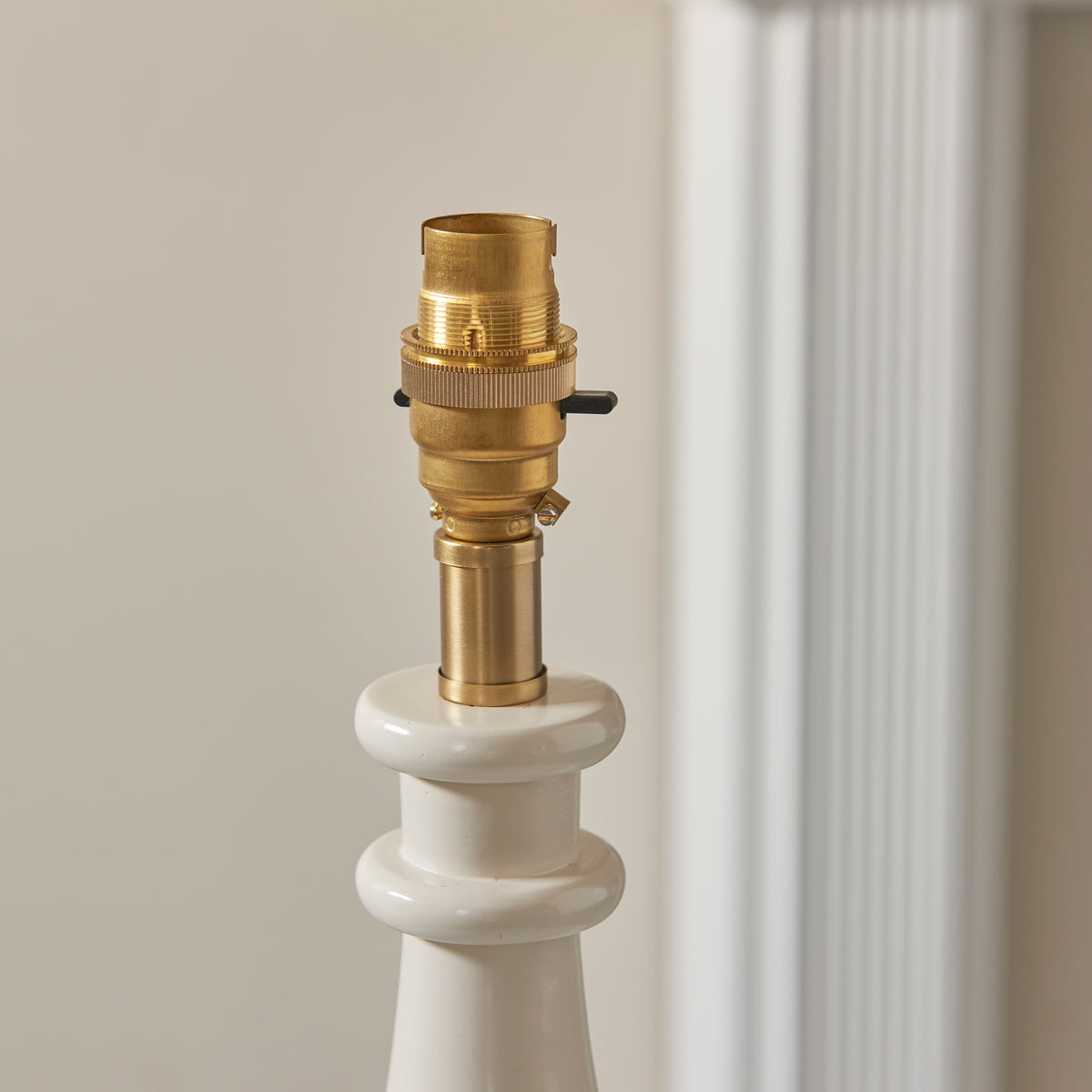 Close-up of the brass bayonet lampholder atop the Myrtle almond white lamp base