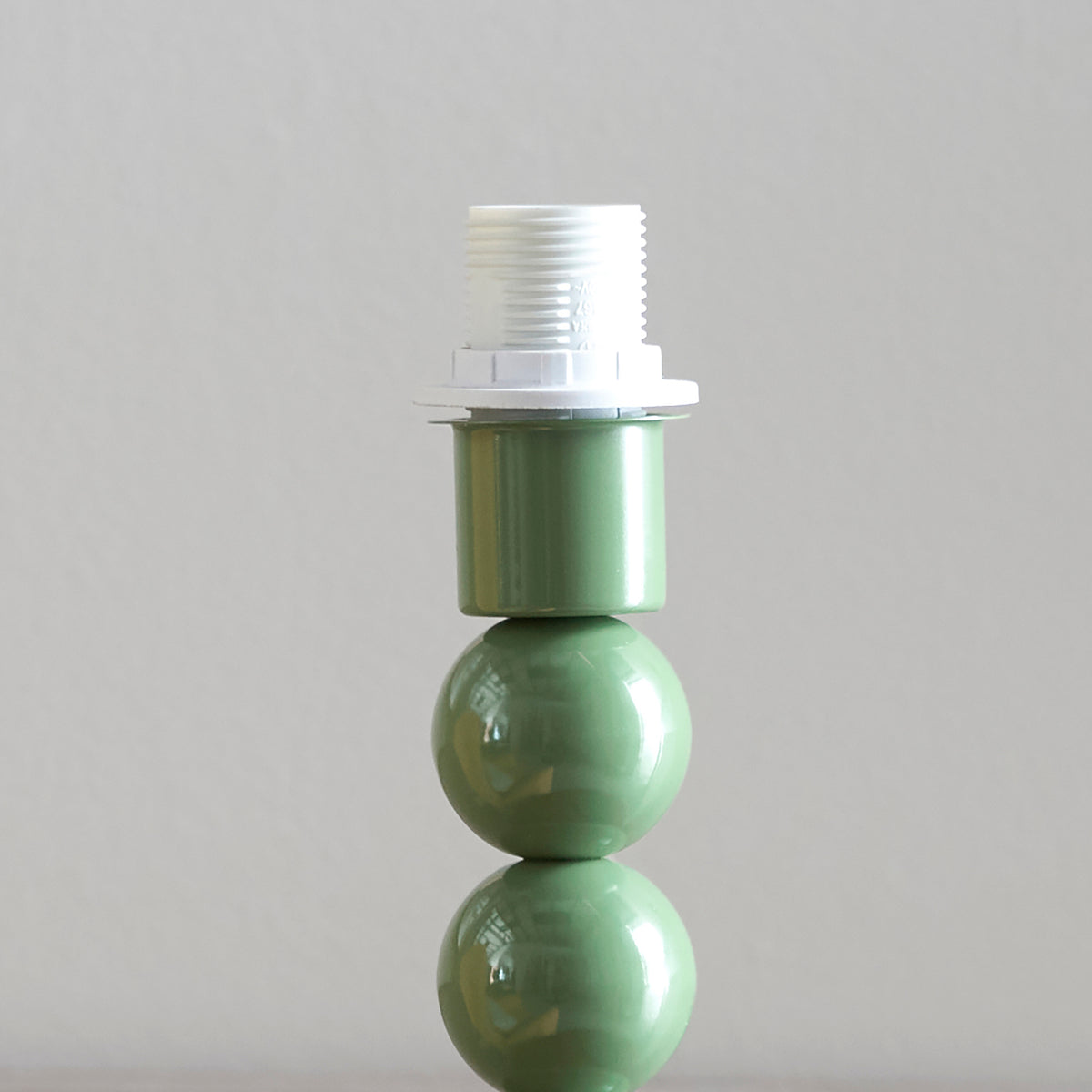 Close-up of the white lampholder on the green ball stem of the Higgledy table lamp