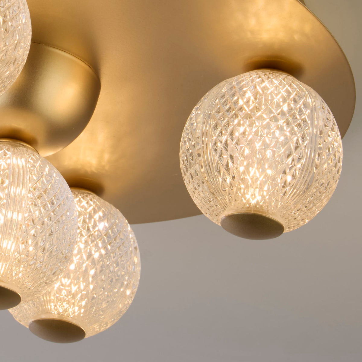 Close-up of an Asteroid textured glass globe below its brushed gold backplate