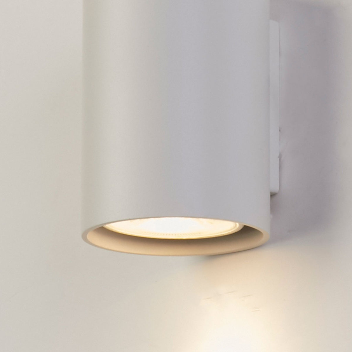 Close-up of Cyls white cylinder's open base and warm downward beam on the wall