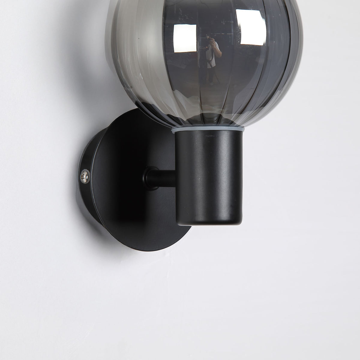 Close-up of Luminsphere's ribbed smoked glass sphere and matt black cylindrical arm and backplate