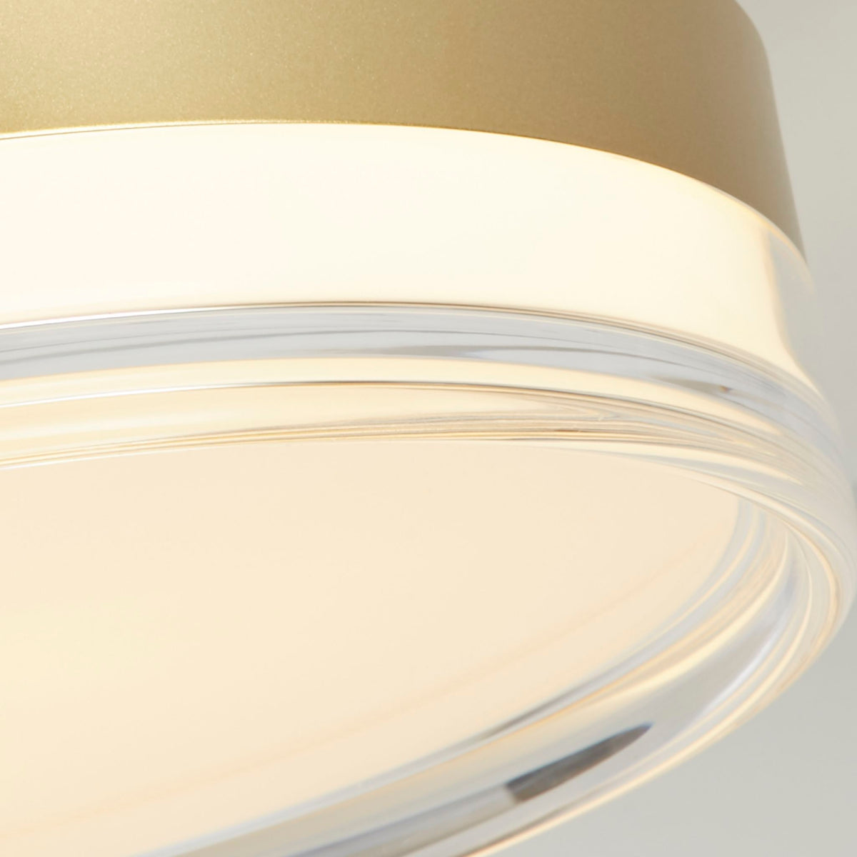 Detail of the Cyprus light's gold drum rim meeting the clear acrylic edge of its opal diffuser