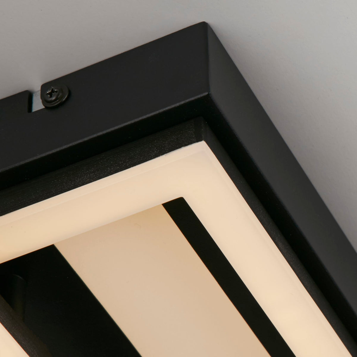 Close-up of the Ovaloid ceiling light's matt black frame corner and glowing opal LED channel